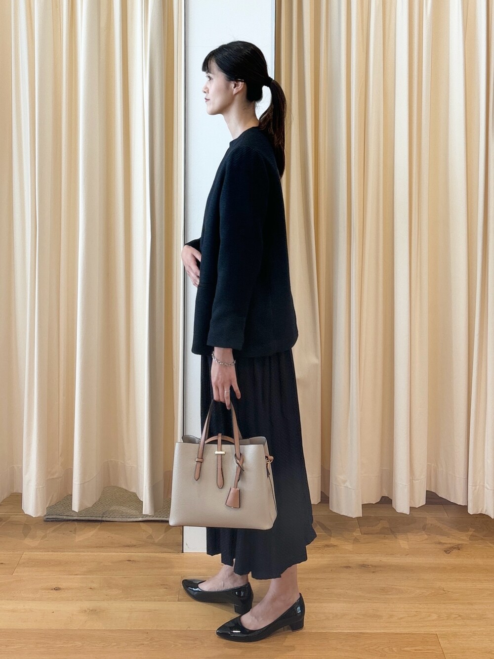 ブルー系のワンピース、ブラック系のパンプス、ベージュ系のトートバッグを着用したレディースの秋コーディネートの5枚目の写真