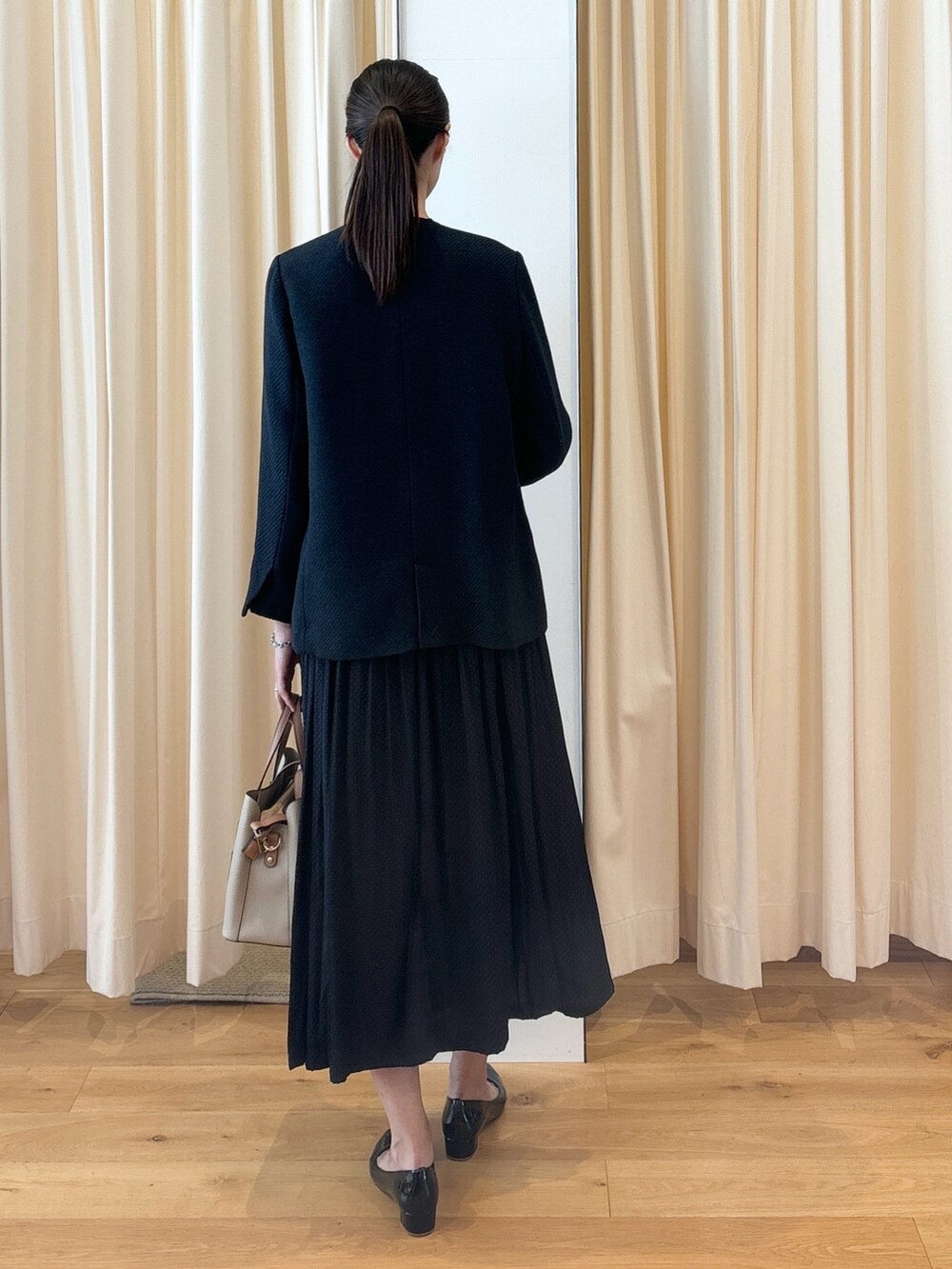 ブルー系のワンピース、ブラック系のパンプス、ベージュ系のトートバッグを着用したレディースの秋コーディネートの6枚目の写真