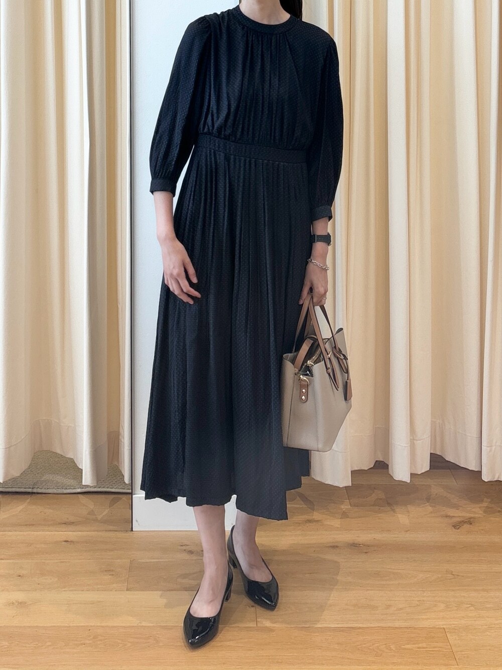 ブルー系のワンピース、ブラック系のパンプス、ベージュ系のトートバッグを着用したレディースの秋コーディネートの3枚目の写真