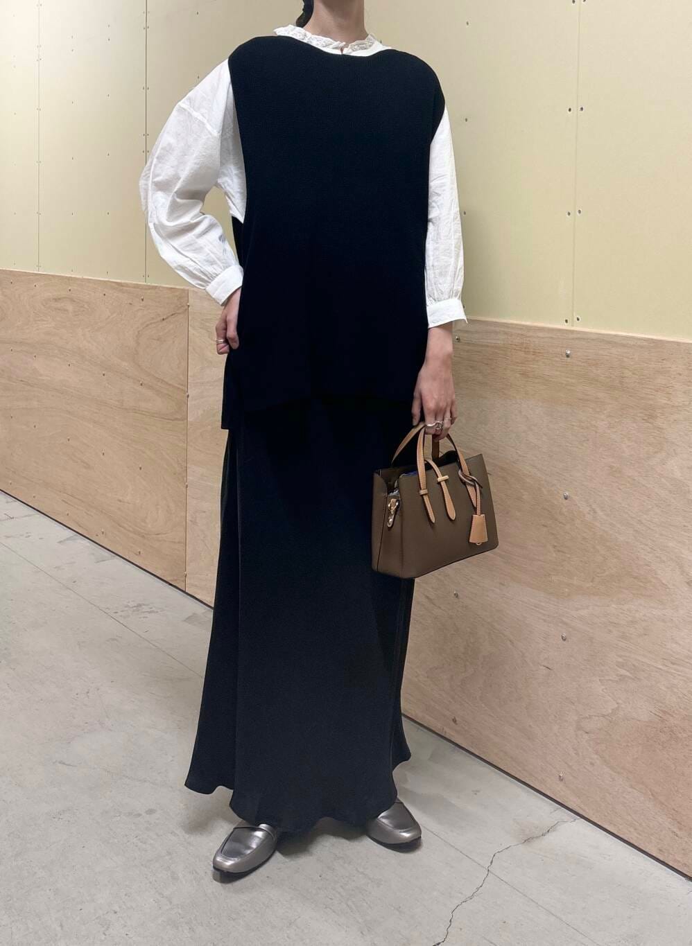 ブラウン系のハンドバッグ、ホワイト系のシャツ/ブラウス、ブラック系のベストを着用したレディースの秋コーディネートの4枚目の写真