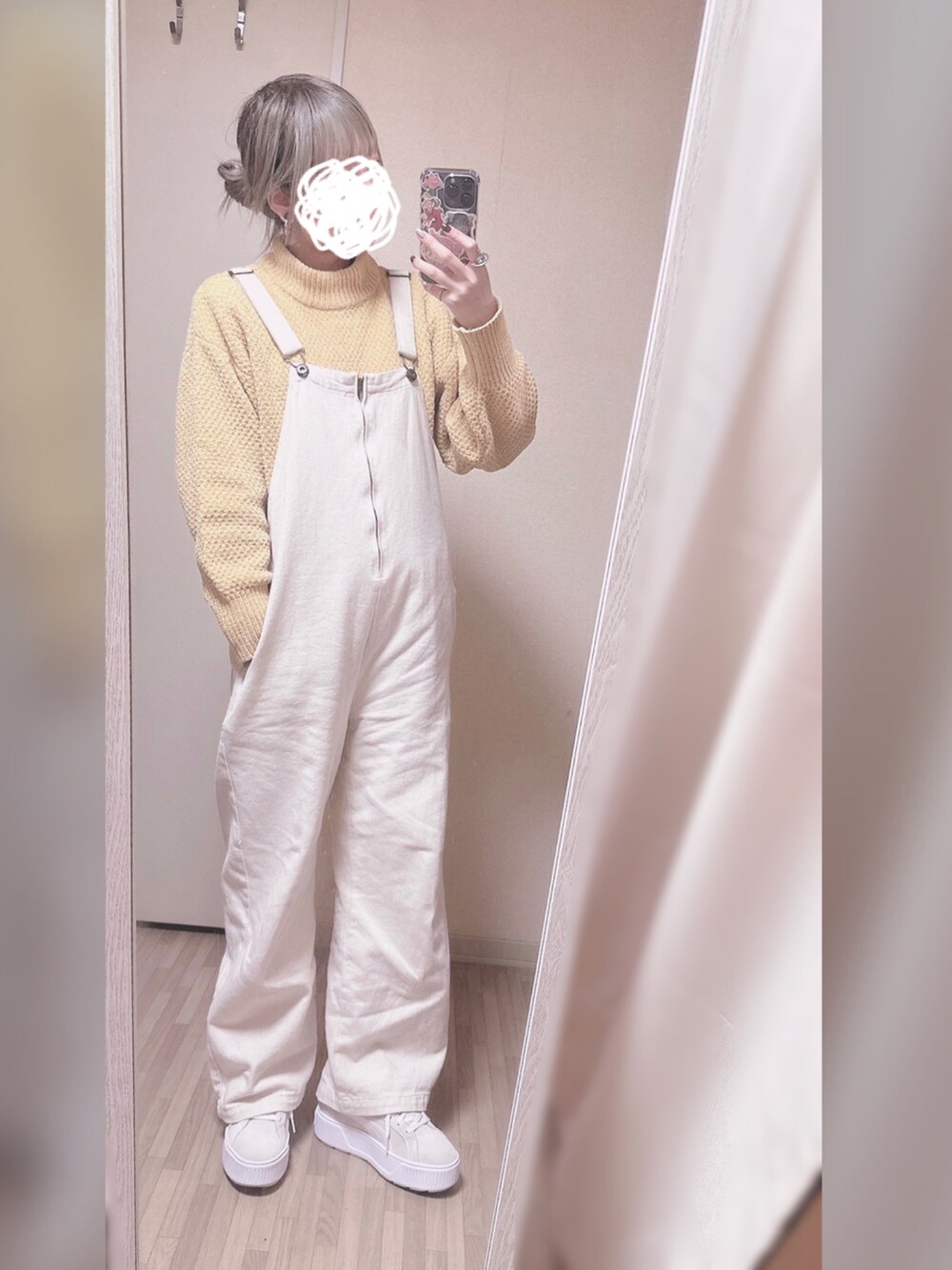 イエロー系のニット/セーター、ホワイト系のサロペット/オーバーオール、ホワイト系のスニーカーを着用したレディースの冬コーディネートの2枚目の写真