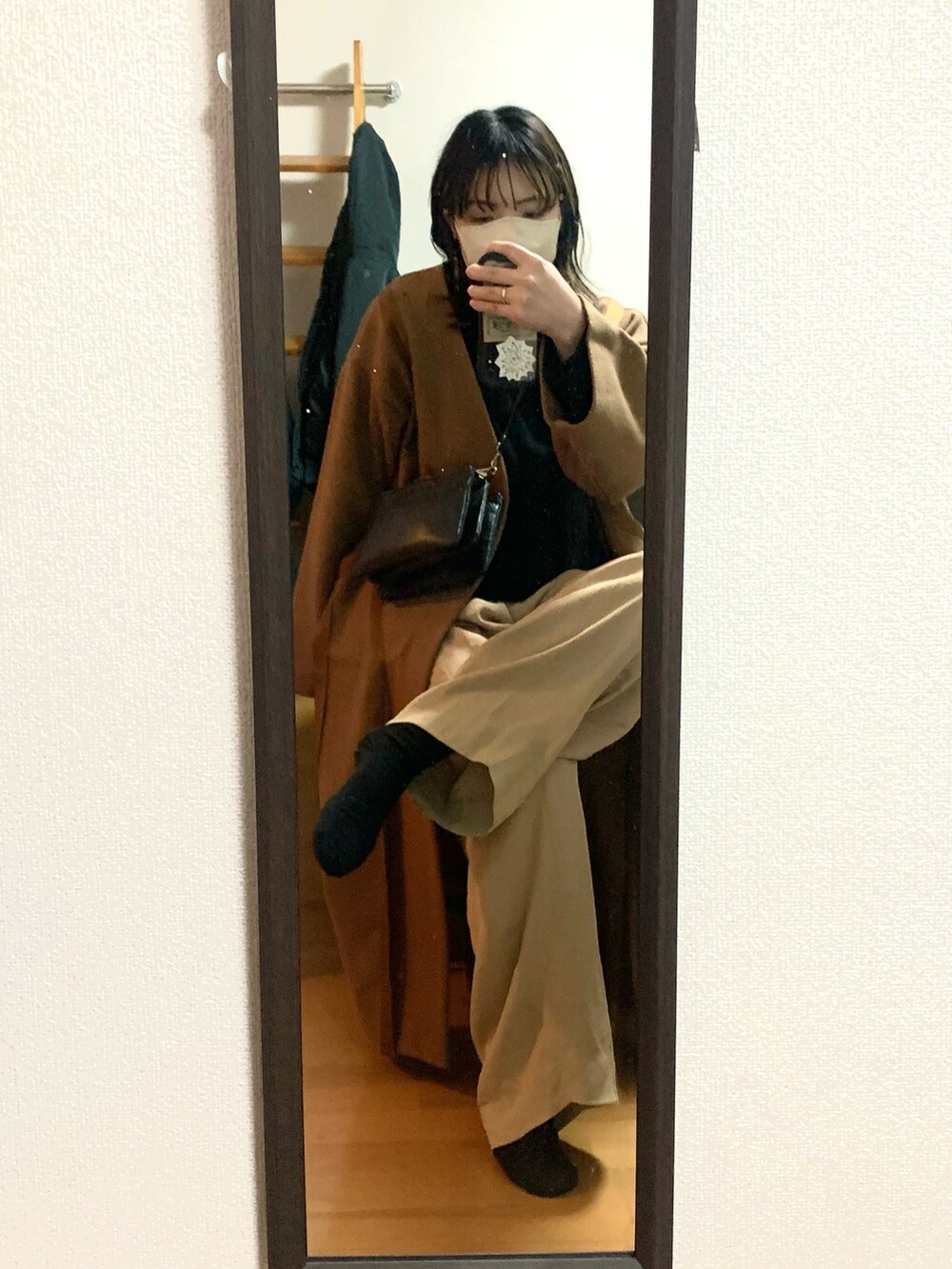 ブラック系のニット/セーター、ベージュ系のパンツ、ブラウン系のノーカラーコートを着用したレディースの冬コーディネートの2枚目の写真