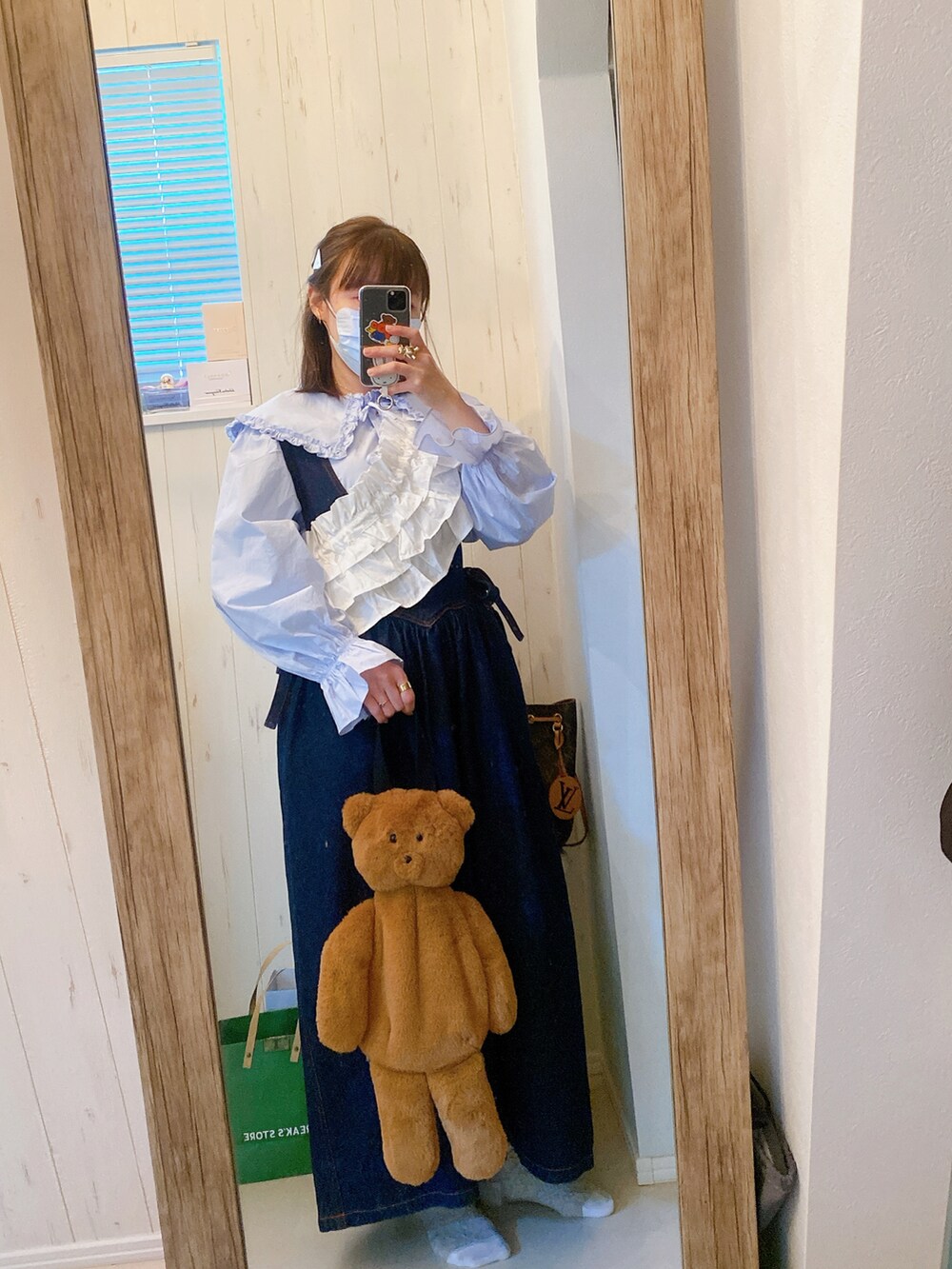 ブルー系のジャンパースカート、ブルー系のシャツ/ブラウス、ブラウン系のハンドバッグを着用したレディースの春コーディネートの2枚目の写真