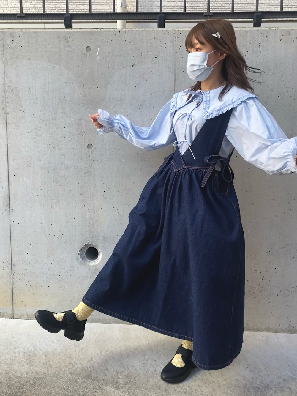 ブラック系のスニーカー、ブルー系のシャツ/ブラウス、ブルー系のジャンパースカートを着用したレディースの冬コーディネートの2枚目の写真