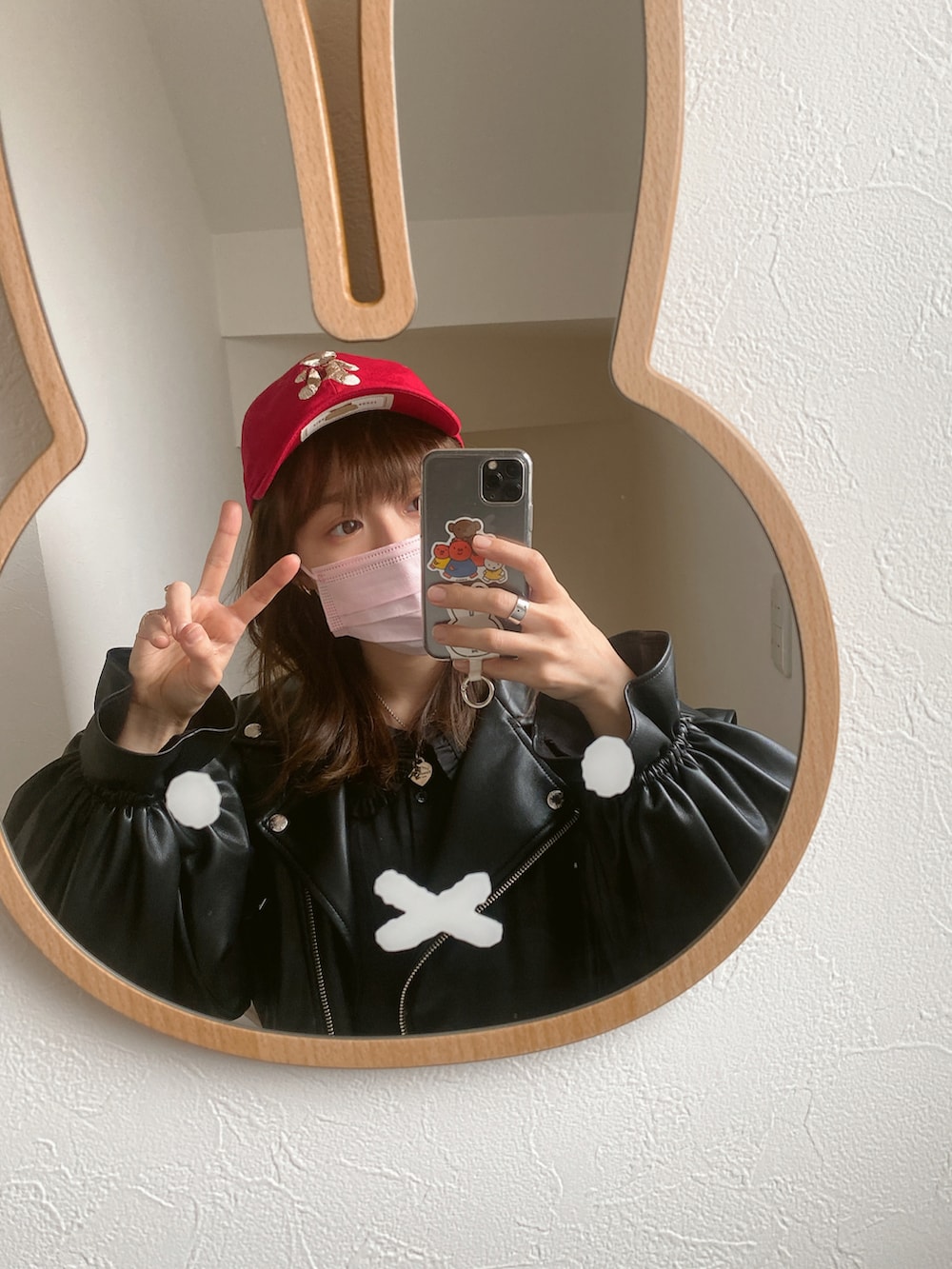 ブラック系のライダースジャケット、ブラック系のワンピース、レッド系のキャップを着用したレディースの冬コーディネートの2枚目の写真