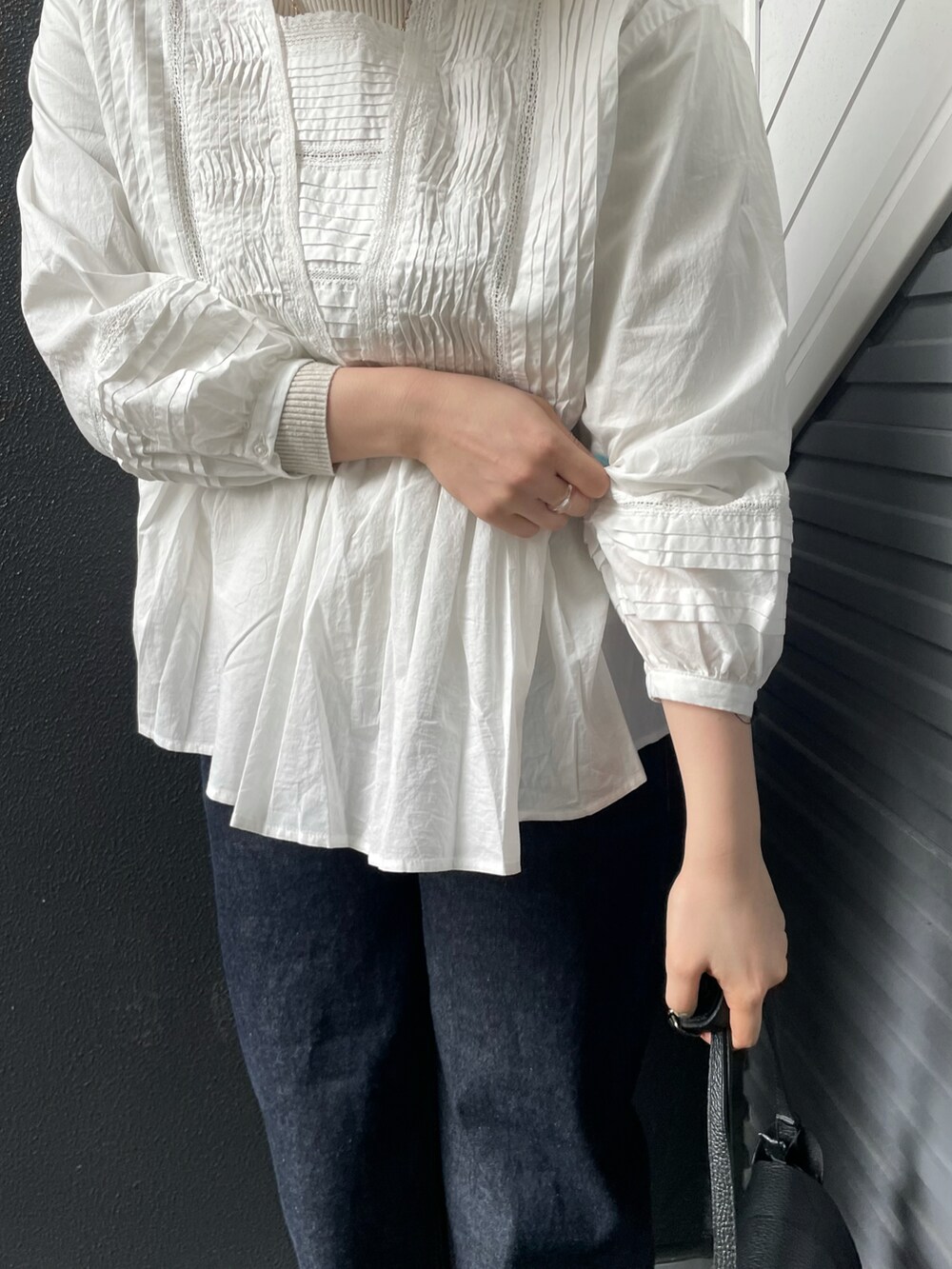 ホワイト系のシャツ/ブラウス、ホワイト系のニット/セーター、ブラック系のショルダーバッグを着用したレディースの冬コーディネートの3枚目の写真