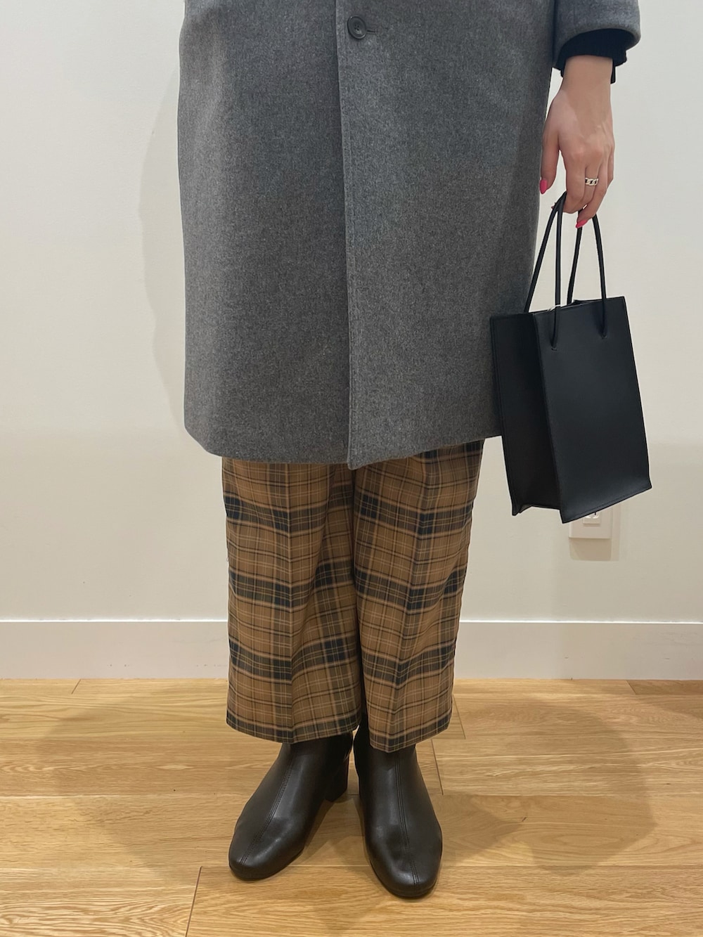 ブラック系のニット/セーター、グレー系のチェスターコート、ブラック系のショルダーバッグを着用したレディースの秋コーディネートの3枚目の写真