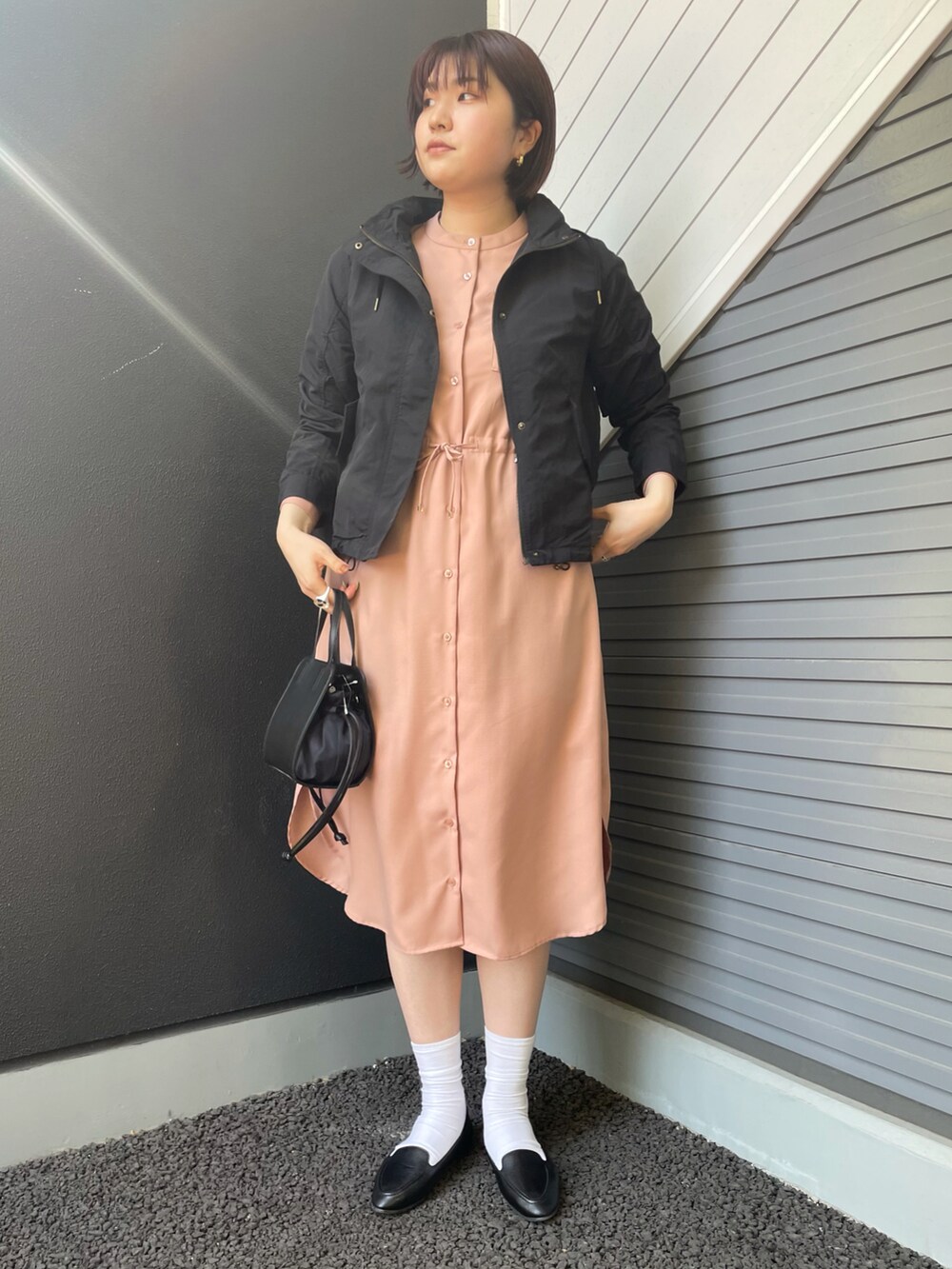 ブラック系のマウンテンパーカー、ピンク系のワンピース、ブラック系のスリッポンを着用したレディースの春コーディネートの2枚目の写真