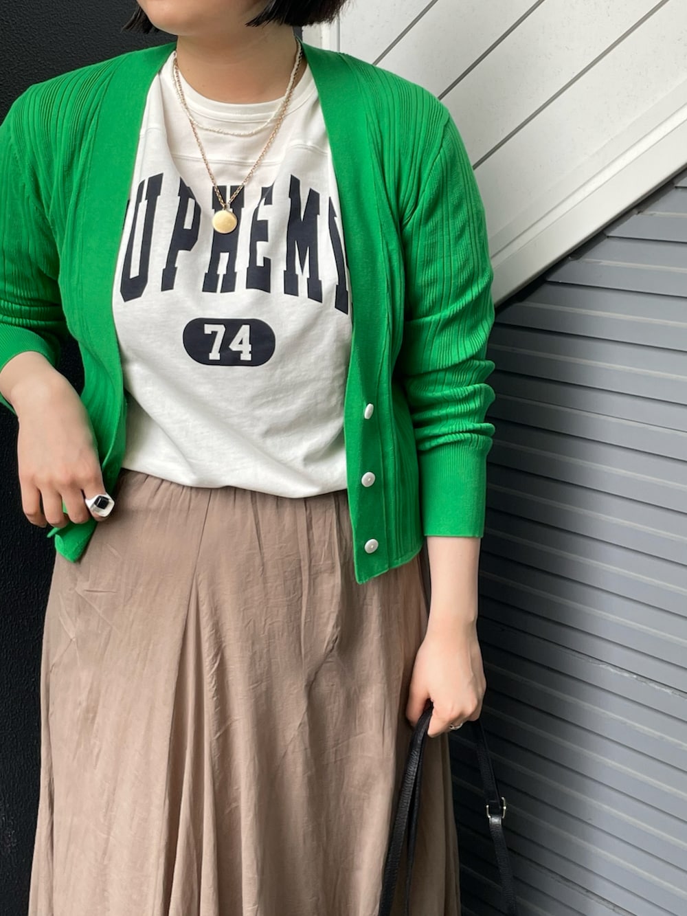 ホワイト系のTシャツ/カットソー、グリーン系のカーディガン/ボレロ、ベージュ系のスカートを着用したレディースの春コーディネートの3枚目の写真