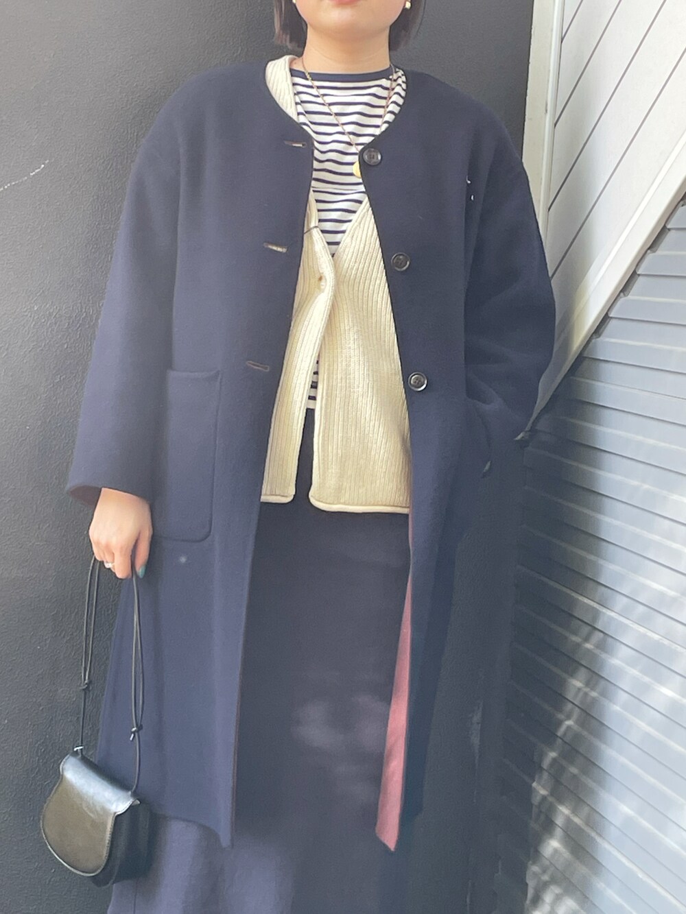 ブルー系のノーカラージャケット、ホワイト系のカーディガン/ボレロ、ブラック系のショルダーバッグを着用したレディースの冬コーディネートの3枚目の写真