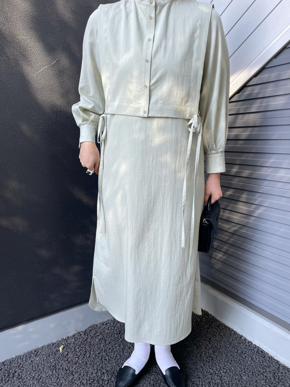 グリーン系のワンピース、ブラック系のバッグ、ブラック系のスリッポンを着用したレディースの冬コーディネートの3枚目の写真