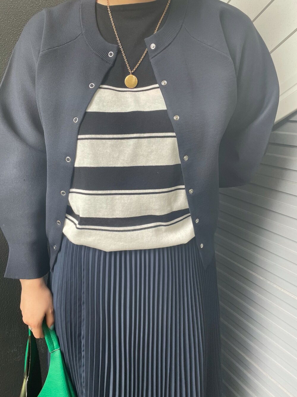 グリーン系のトートバッグ、ブルー系のスカート、ブラック系のローファーを着用したレディースの冬コーディネートの4枚目の写真