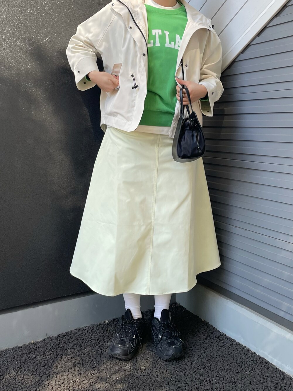 ホワイト系のマウンテンパーカー、グリーン系のスウェット、ブラック系のショルダーバッグを着用したレディースの冬コーディネートの3枚目の写真