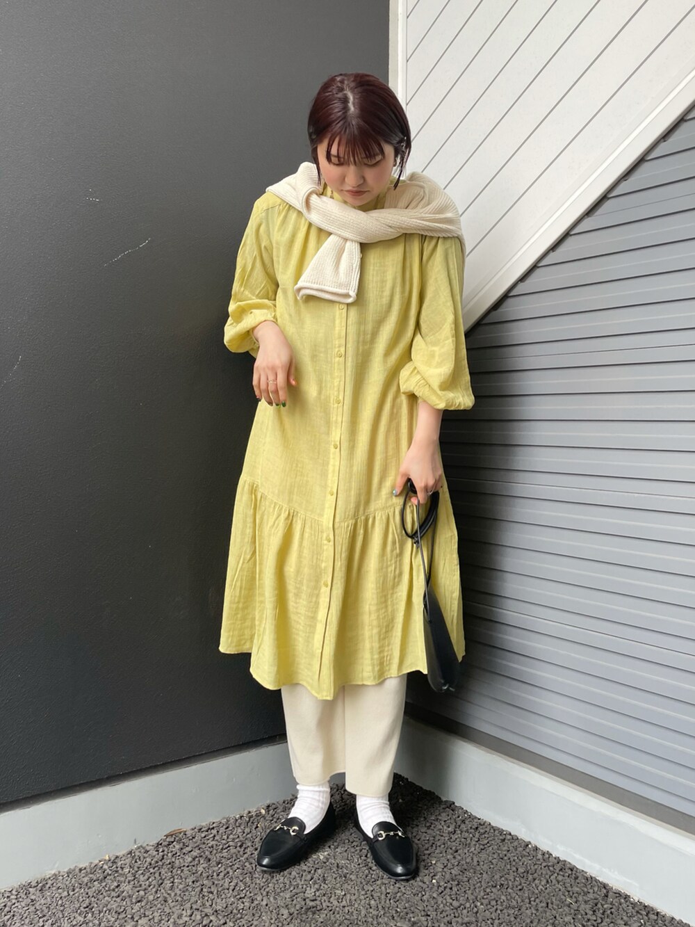 ブラック系のローファー、ブラック系のショルダーバッグ、イエロー系のワンピースを着用したレディースの冬コーディネートの2枚目の写真