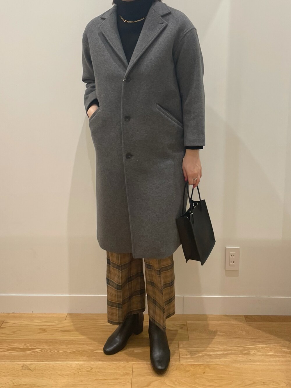 ブラック系のニット/セーター、グレー系のチェスターコート、ブラック系のショルダーバッグを着用したレディースの秋コーディネートの2枚目の写真