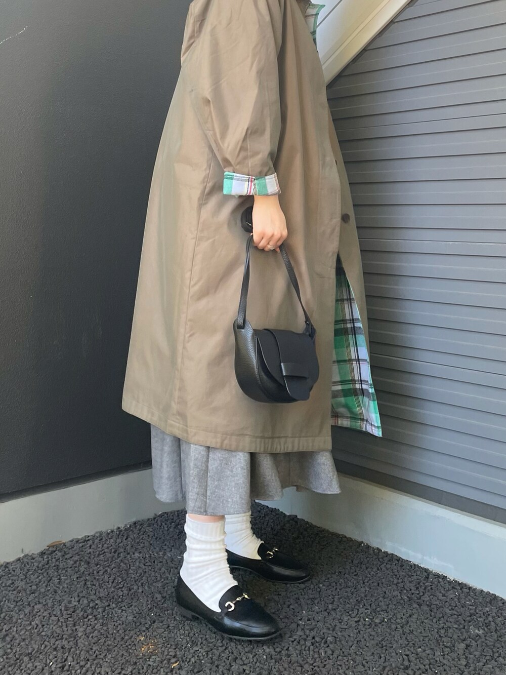 グリーン系のステンカラーコート、グレー系のスカート、ブラック系のショルダーバッグを着用したレディースの冬コーディネートの2枚目の写真