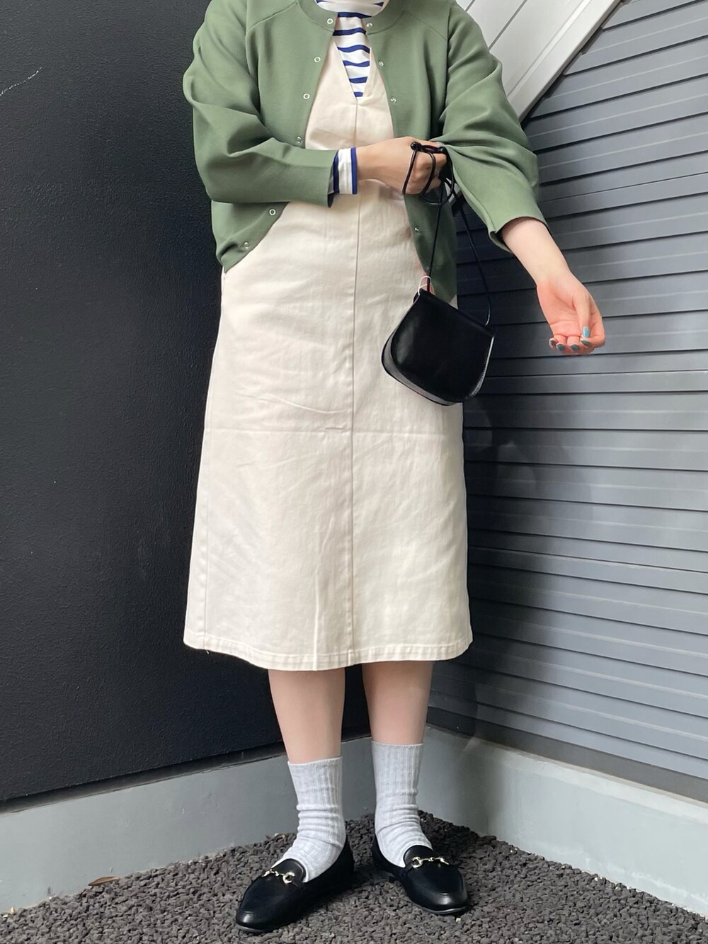 ブラック系のショルダーバッグ、グリーン系のニット/セーター、ホワイト系のワンピースを着用したレディースの冬コーディネートの3枚目の写真