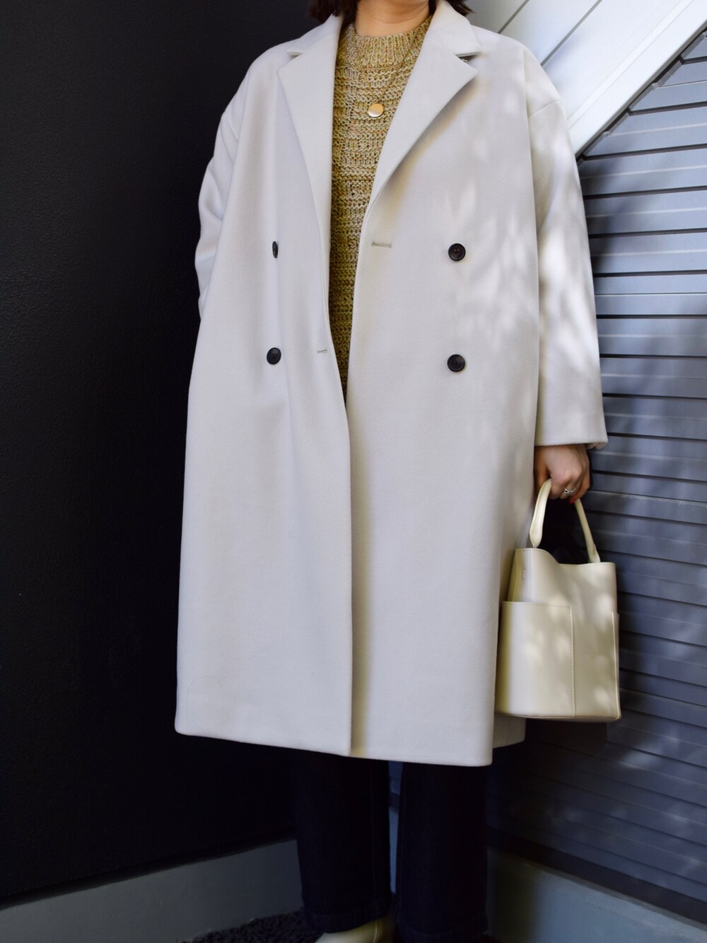 グレー系のチェスターコート、ベージュ系のワンピース、ホワイト系のトートバッグを着用したレディースの秋コーディネートの2枚目の写真