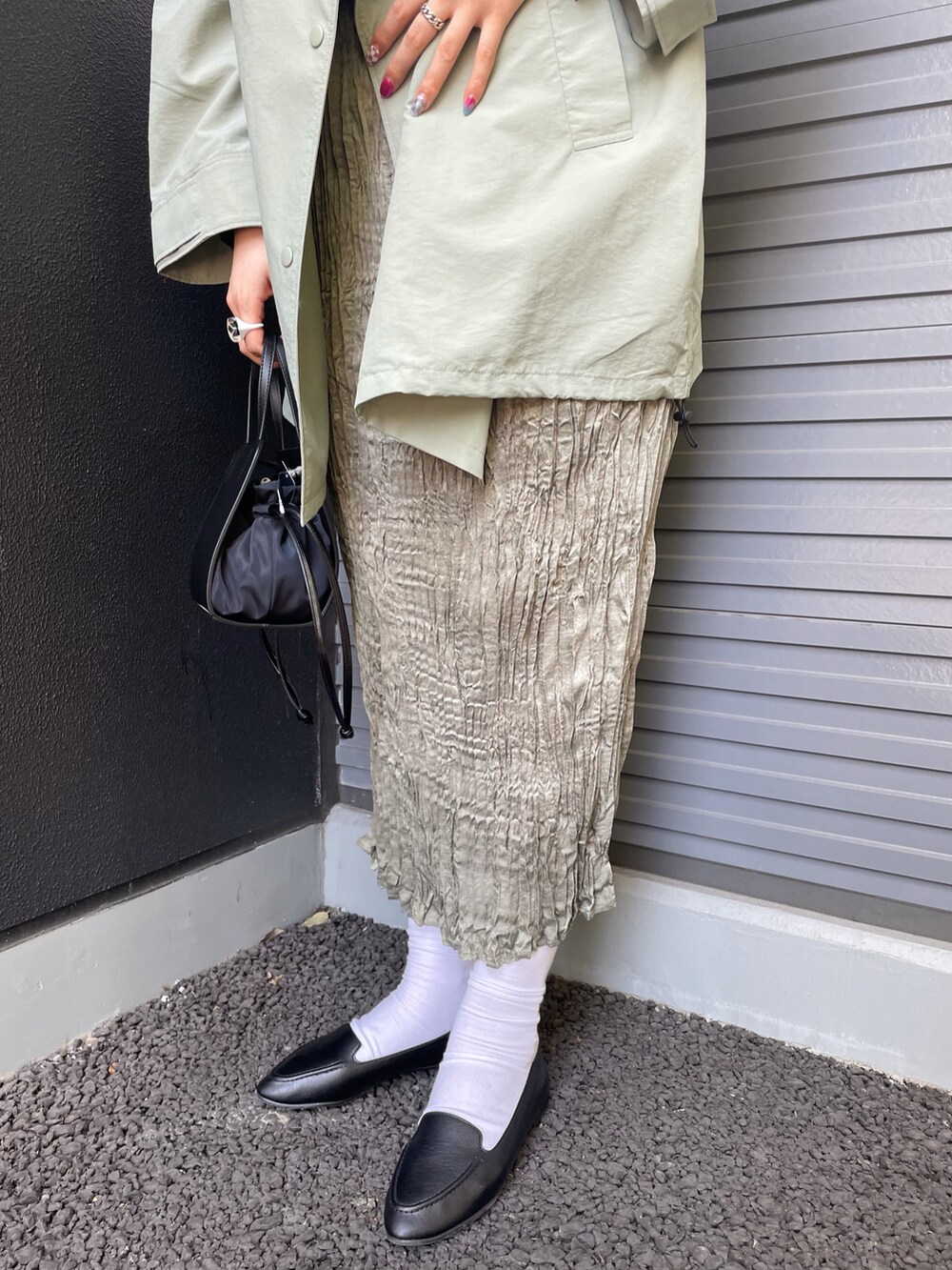 グリーン系のポンチョ、ブルー系のワンピース、ブラック系のスリッポンを着用したレディースの春コーディネートの4枚目の写真