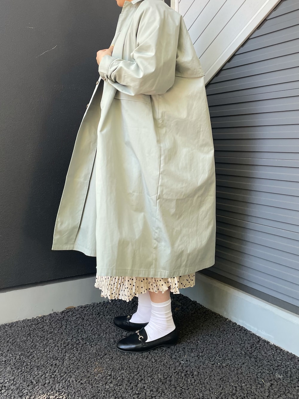 グリーン系のステンカラーコート、ブルー系のスウェット、ホワイト系のスカートを着用したレディースの冬コーディネートの4枚目の写真