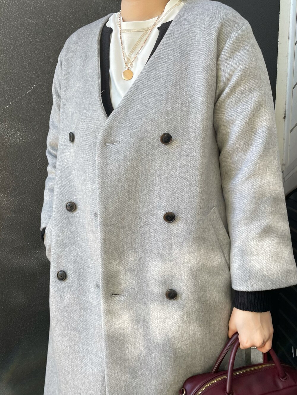 レッド系のボストンバッグ、グレー系のその他アウター、ホワイト系のTシャツ/カットソーを着用したレディースの冬コーディネートの3枚目の写真