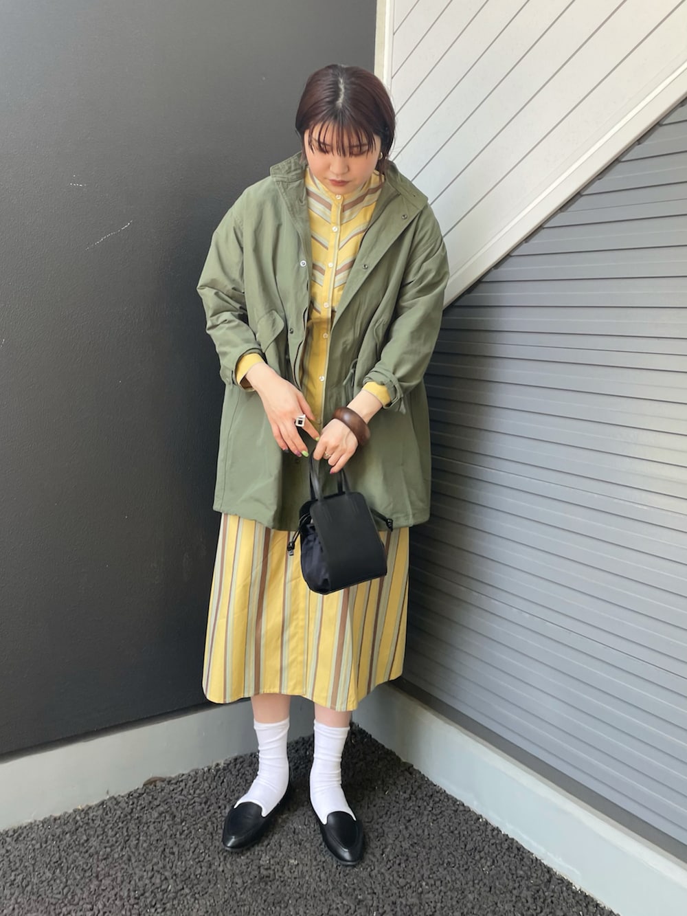グリーン系のモッズコート、イエロー系のワンピース、ブラック系のスリッポンを着用したレディースの春コーディネートの2枚目の写真