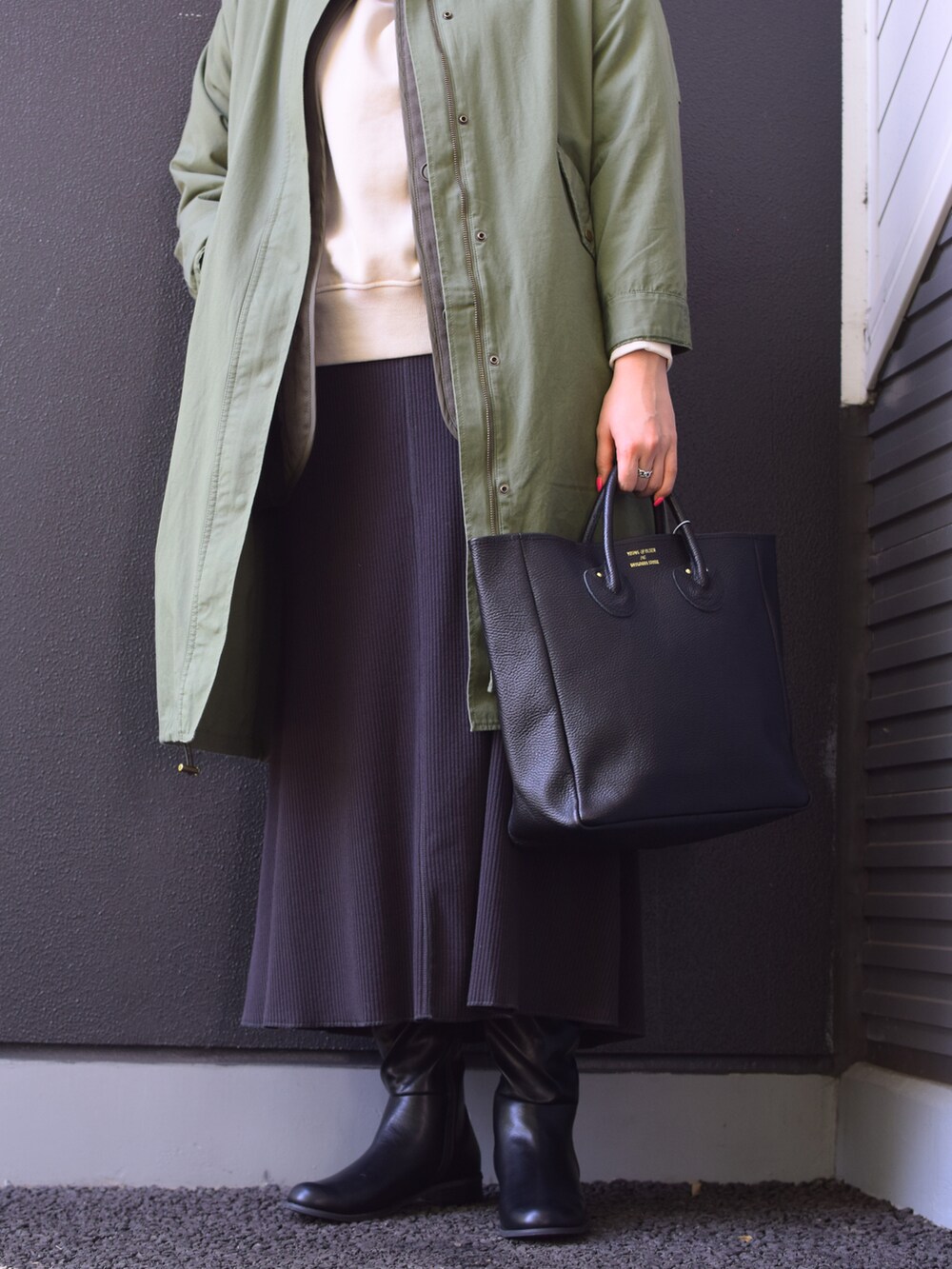 グリーン系のミリタリージャケット、ブラック系のトートバッグ、グレー系のスカートを着用したレディースの冬コーディネートの3枚目の写真