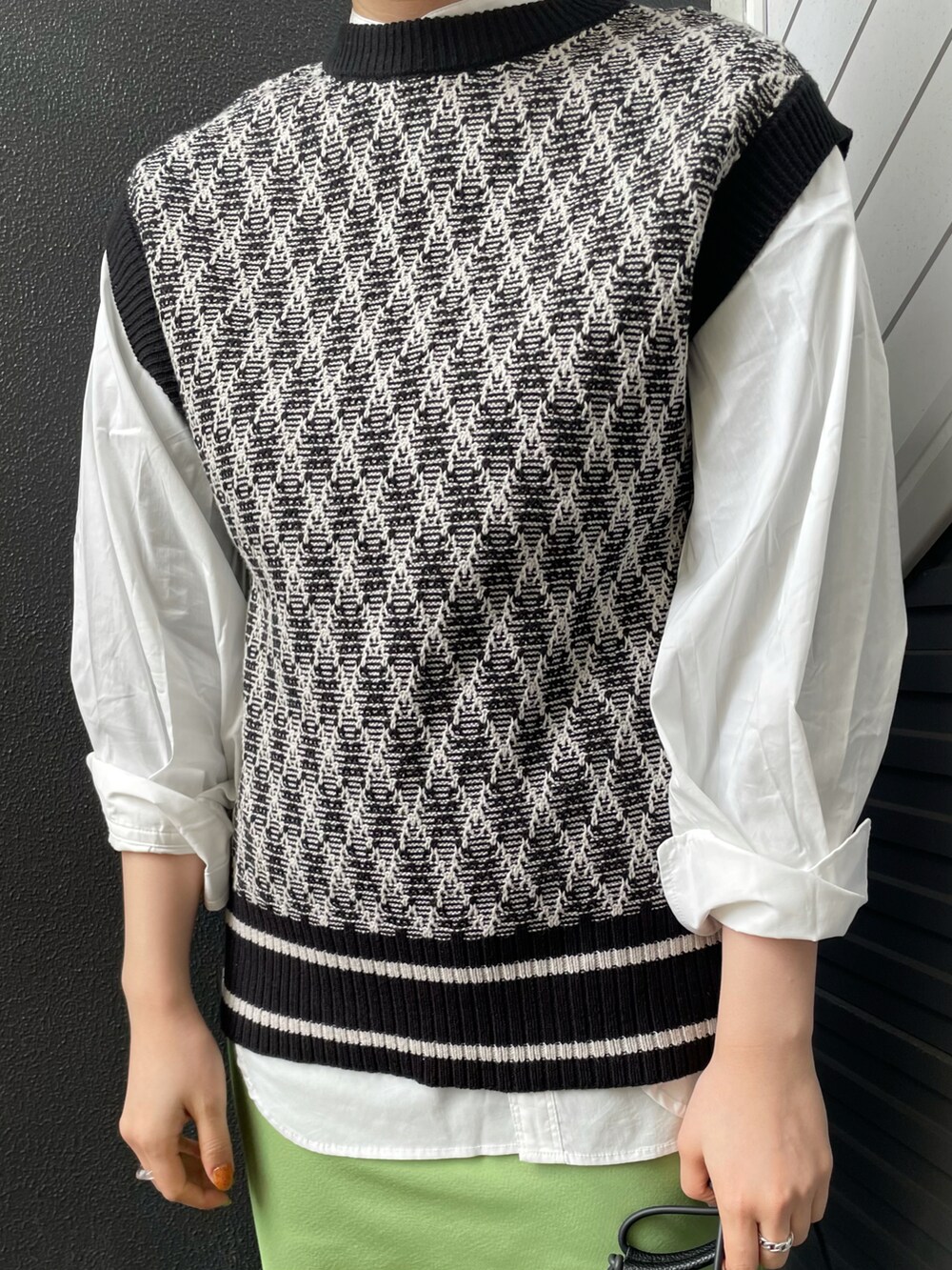 ブラック系のベスト、ホワイト系のシャツ/ブラウス、グリーン系のスカートを着用したレディースの冬コーディネートの3枚目の写真