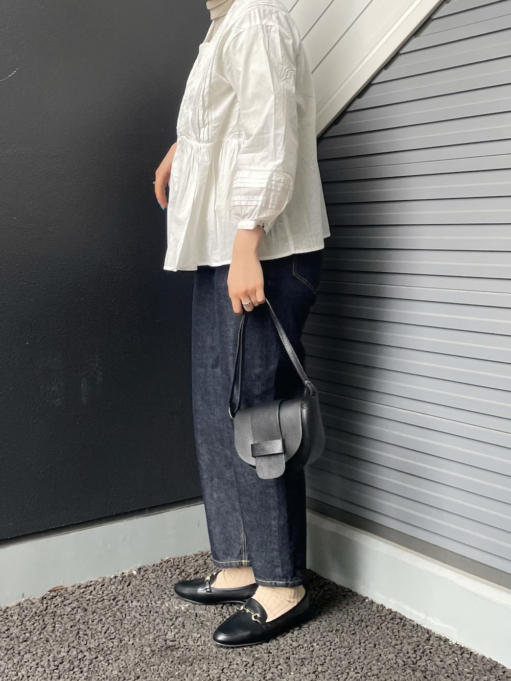 ホワイト系のシャツ/ブラウス、ホワイト系のニット/セーター、ブラック系のショルダーバッグを着用したレディースの冬コーディネートの2枚目の写真