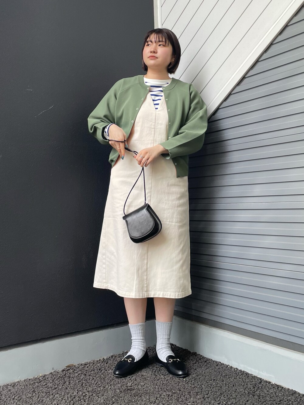 ブラック系のショルダーバッグ、グリーン系のニット/セーター、ホワイト系のワンピースを着用したレディースの冬コーディネートの2枚目の写真