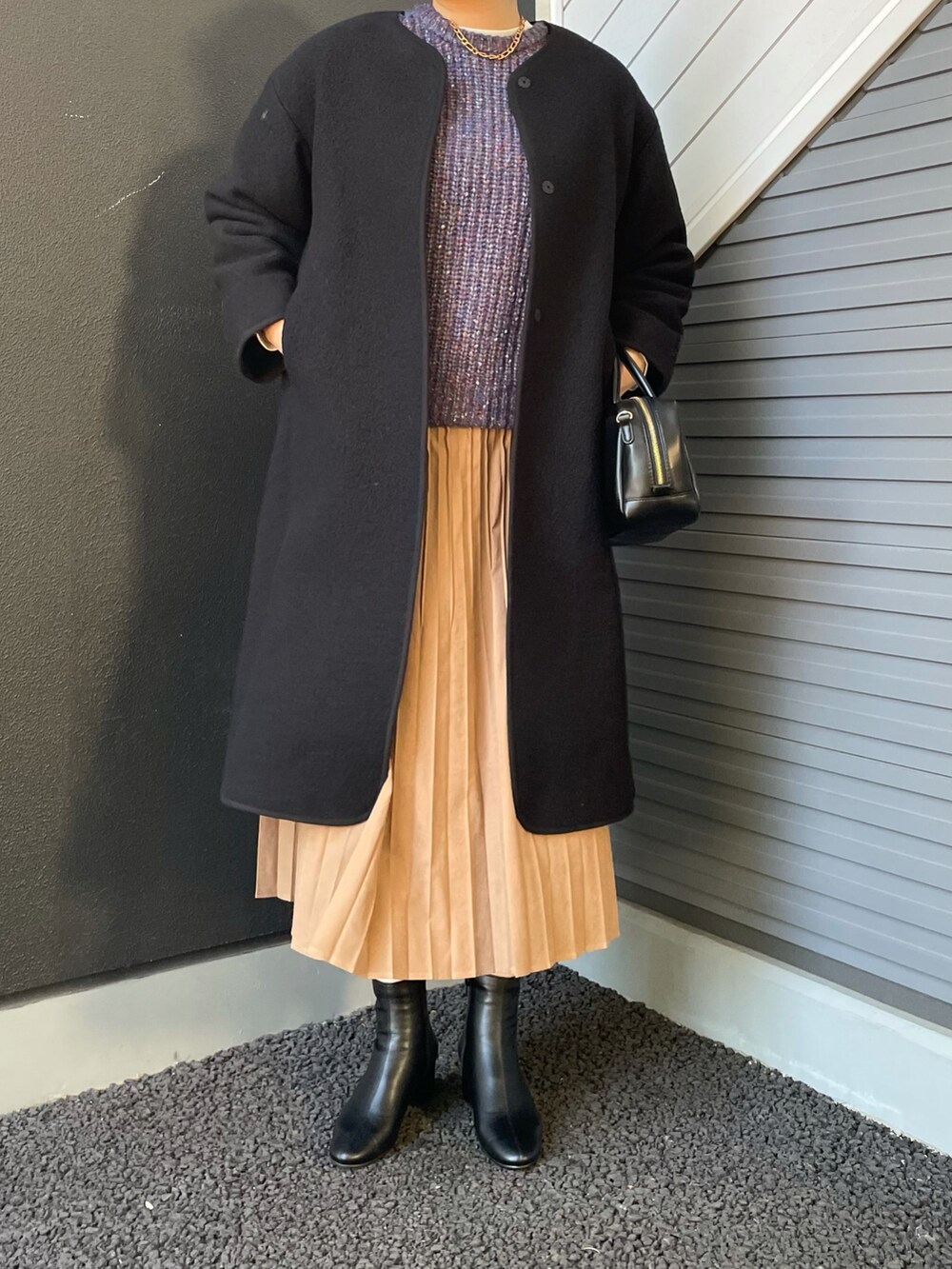 ブラック系のブーツ、ブラック系のボストンバッグ、ブラック系のその他アウターを着用したレディースの冬コーディネートの2枚目の写真