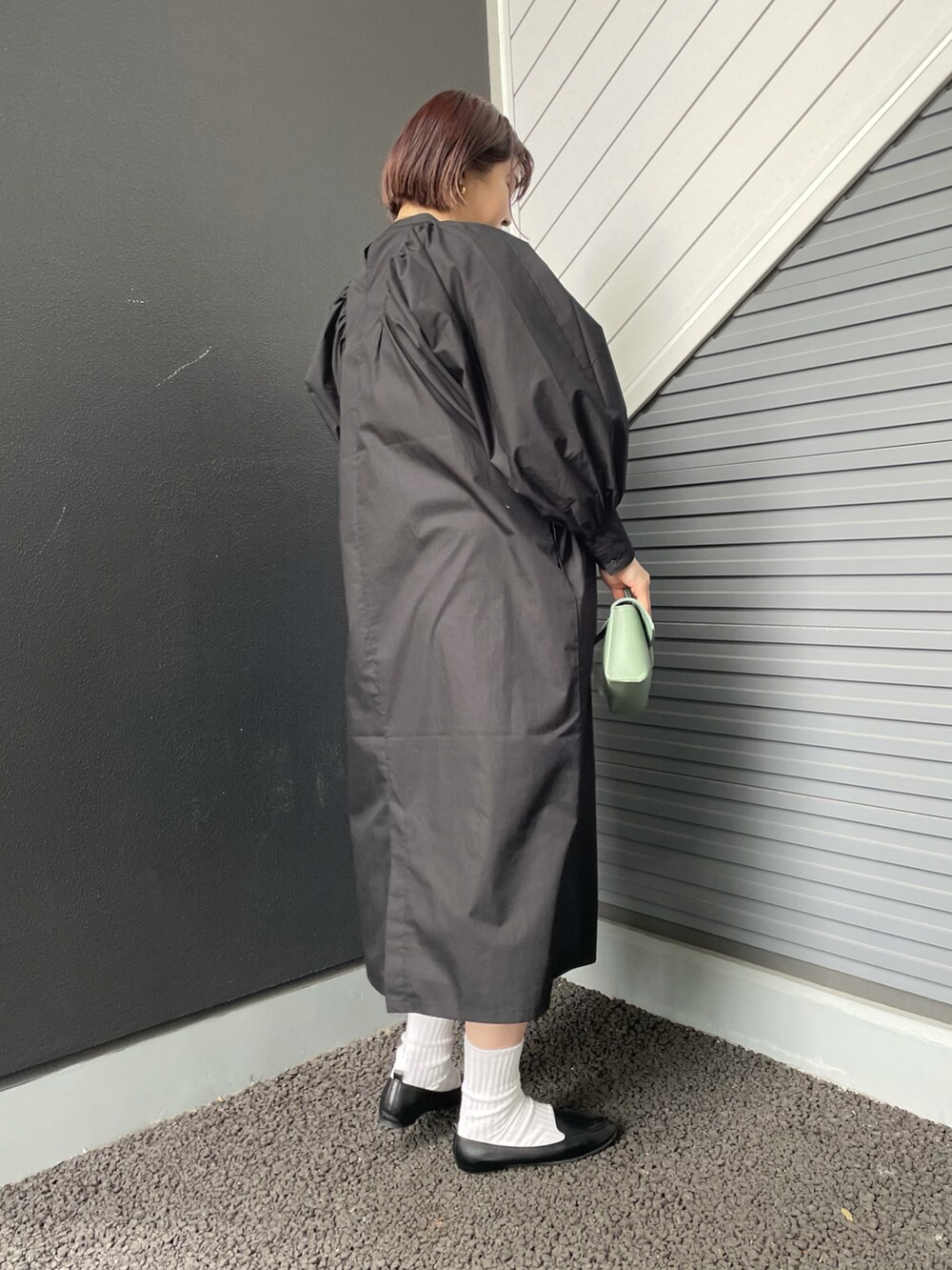 グリーン系のショルダーバッグ、ブラック系のワンピース、ブラック系のスリッポンを着用したレディースの冬コーディネートの2枚目の写真