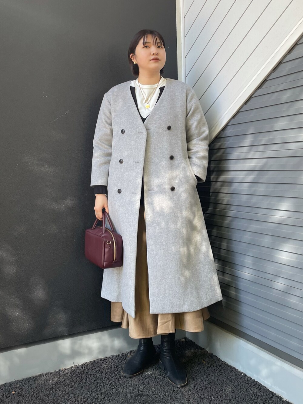 レッド系のボストンバッグ、グレー系のその他アウター、ホワイト系のTシャツ/カットソーを着用したレディースの冬コーディネートの2枚目の写真