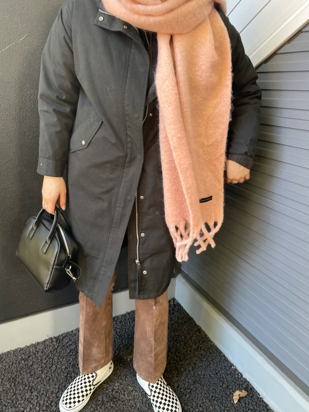 ブラック系のミリタリージャケット、ブラック系のボストンバッグ、ブラウン系のその他パンツを着用したレディースの冬コーディネートの3枚目の写真