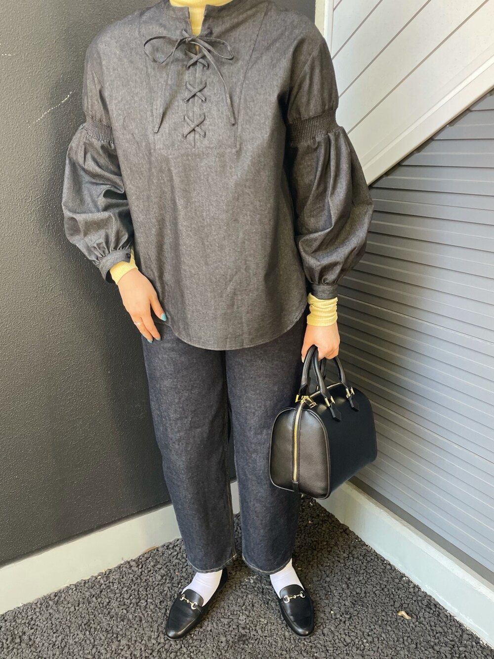 イエロー系のTシャツ/カットソー、ブラック系のシャツ/ブラウス、ブラック系のボストンバッグを着用したレディースの冬コーディネートの3枚目の写真