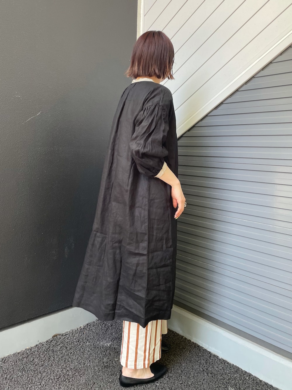 ブラック系のショルダーバッグ、ブラック系のスリッポン、ホワイト系のパンツを着用したレディースの春コーディネートの2枚目の写真