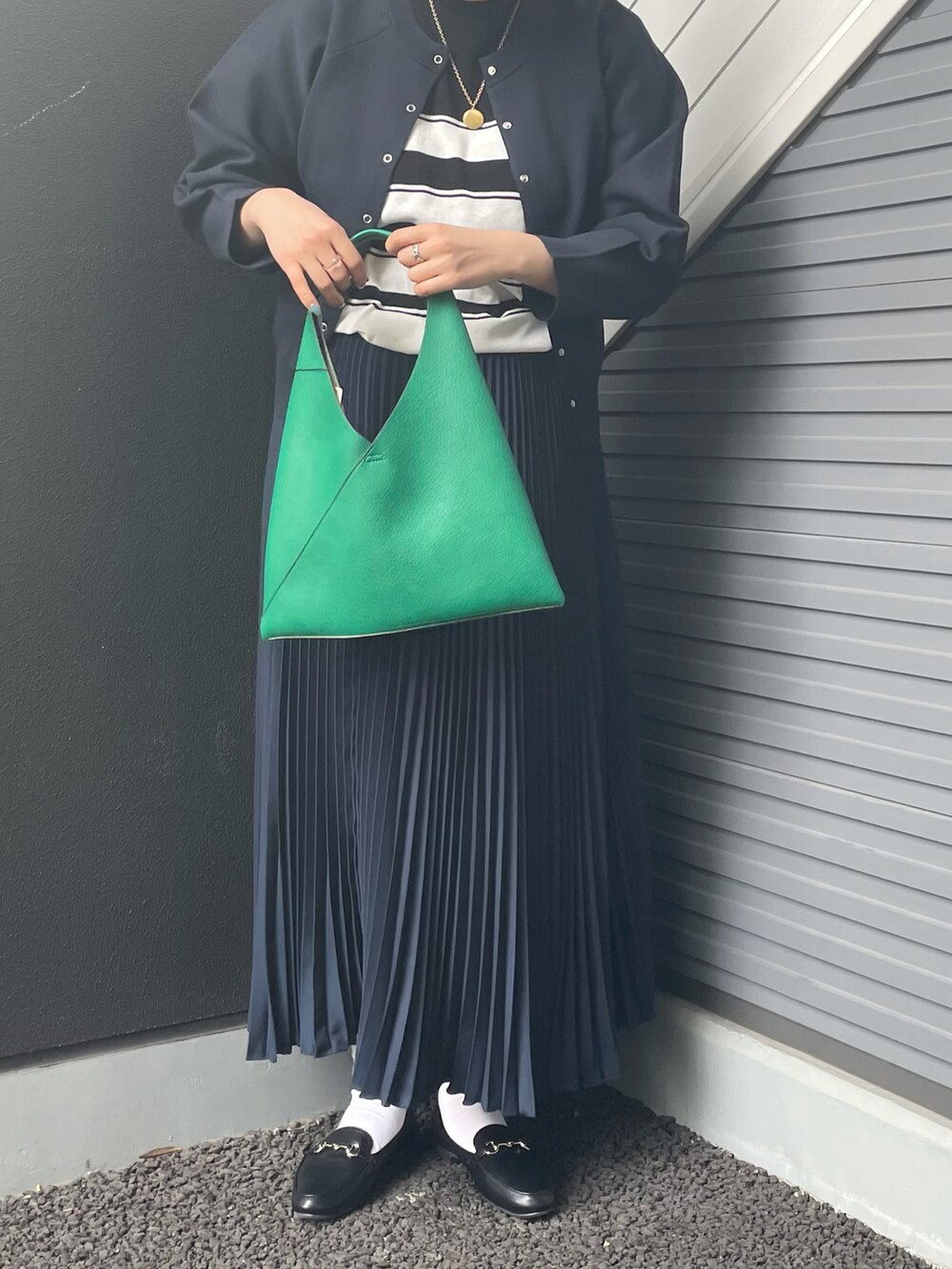 グリーン系のトートバッグ、ブルー系のスカート、ブラック系のローファーを着用したレディースの冬コーディネートの2枚目の写真