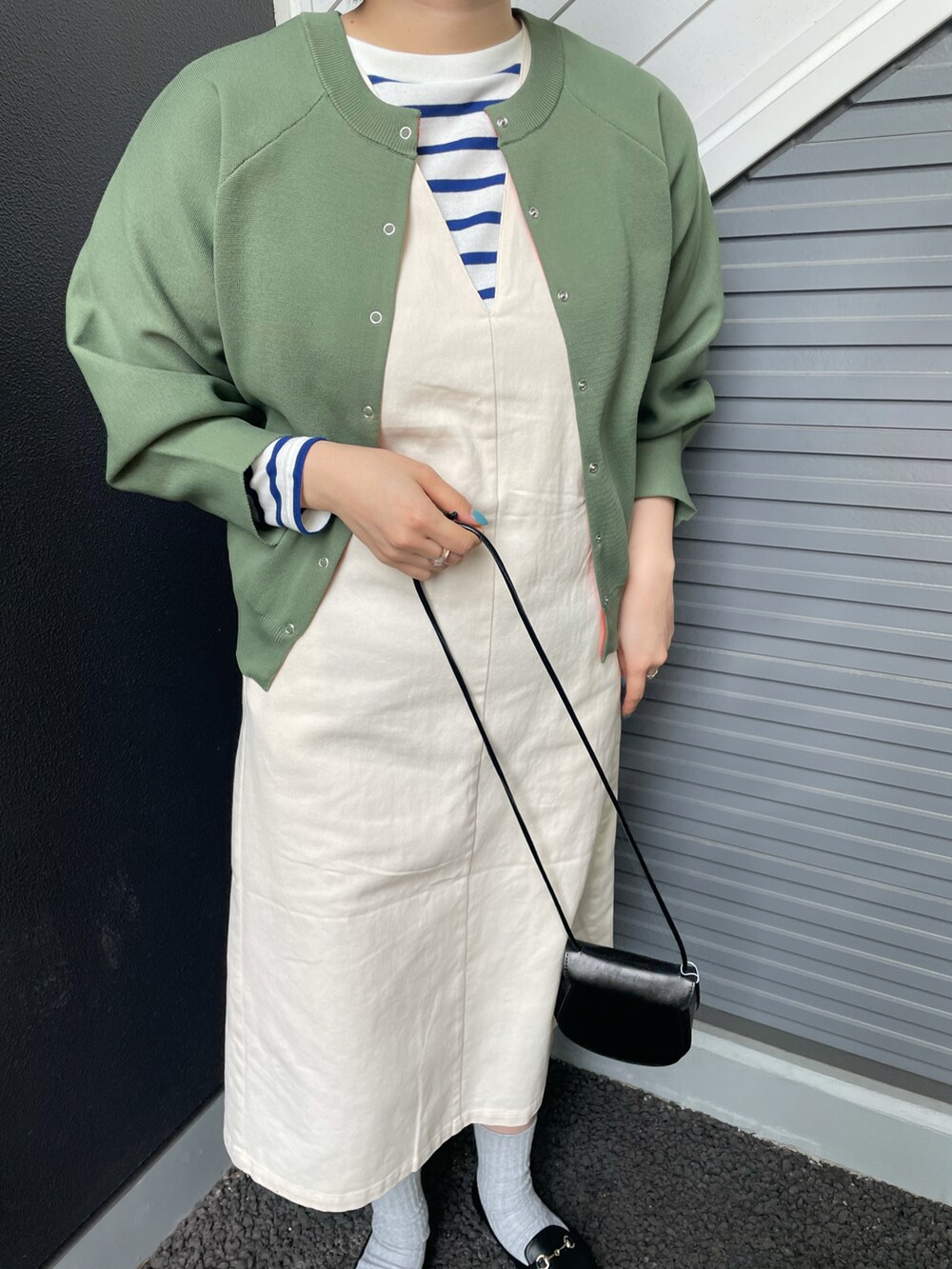 ブラック系のショルダーバッグ、グリーン系のニット/セーター、ホワイト系のワンピースを着用したレディースの冬コーディネートの4枚目の写真