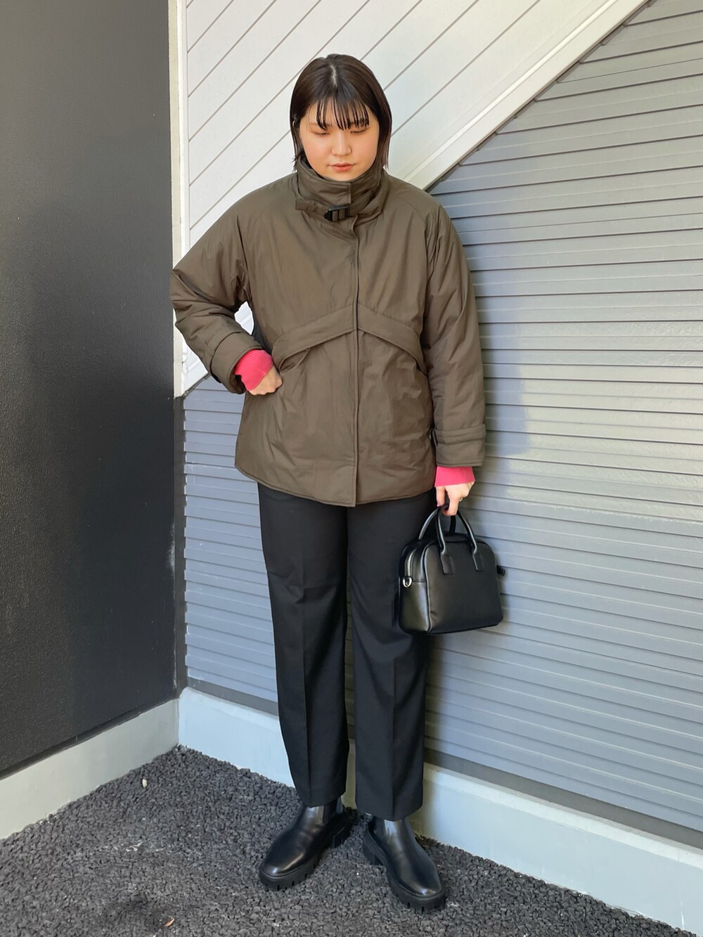 グリーン系のダウンジャケット/コート、ピンク系のニット/セーター、ブラック系のボストンバッグを着用したレディースの秋コーディネートの2枚目の写真