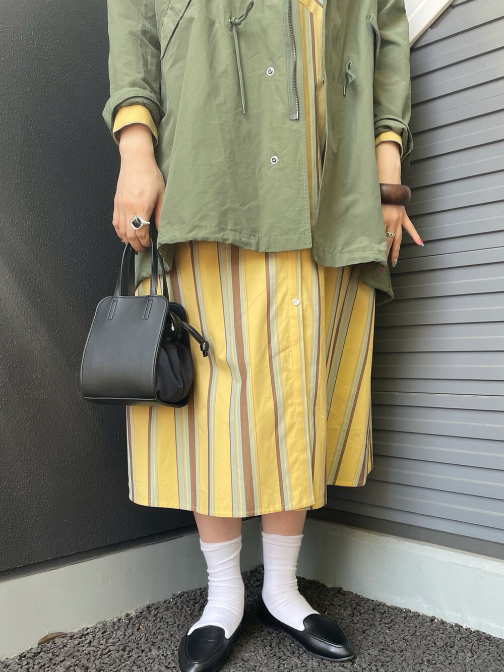 グリーン系のモッズコート、イエロー系のワンピース、ブラック系のスリッポンを着用したレディースの春コーディネートの4枚目の写真