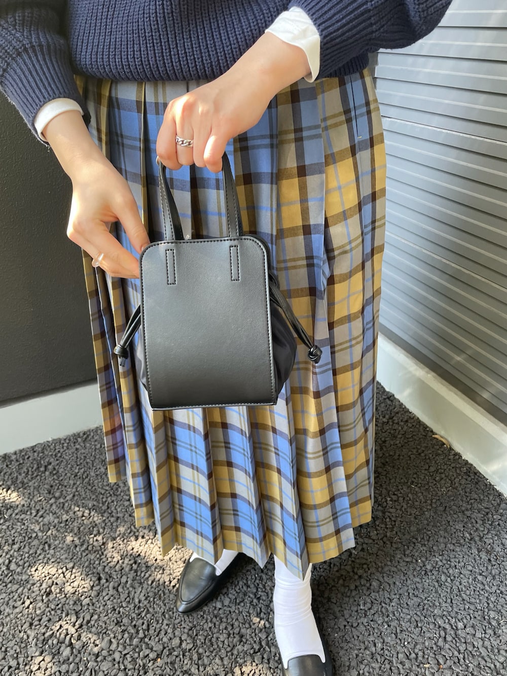 ブルー系のニット/セーター、ブルー系のスカート、ブラック系のショルダーバッグを着用したレディースの冬コーディネートの5枚目の写真