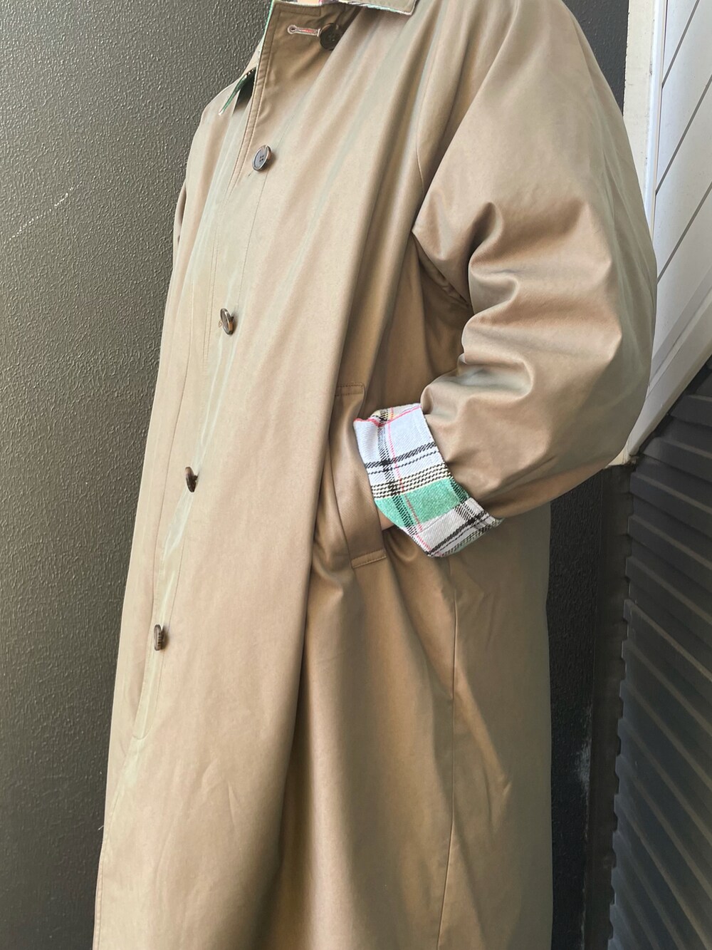 グリーン系のステンカラーコート、グレー系のスカート、ブラック系のショルダーバッグを着用したレディースの冬コーディネートの4枚目の写真