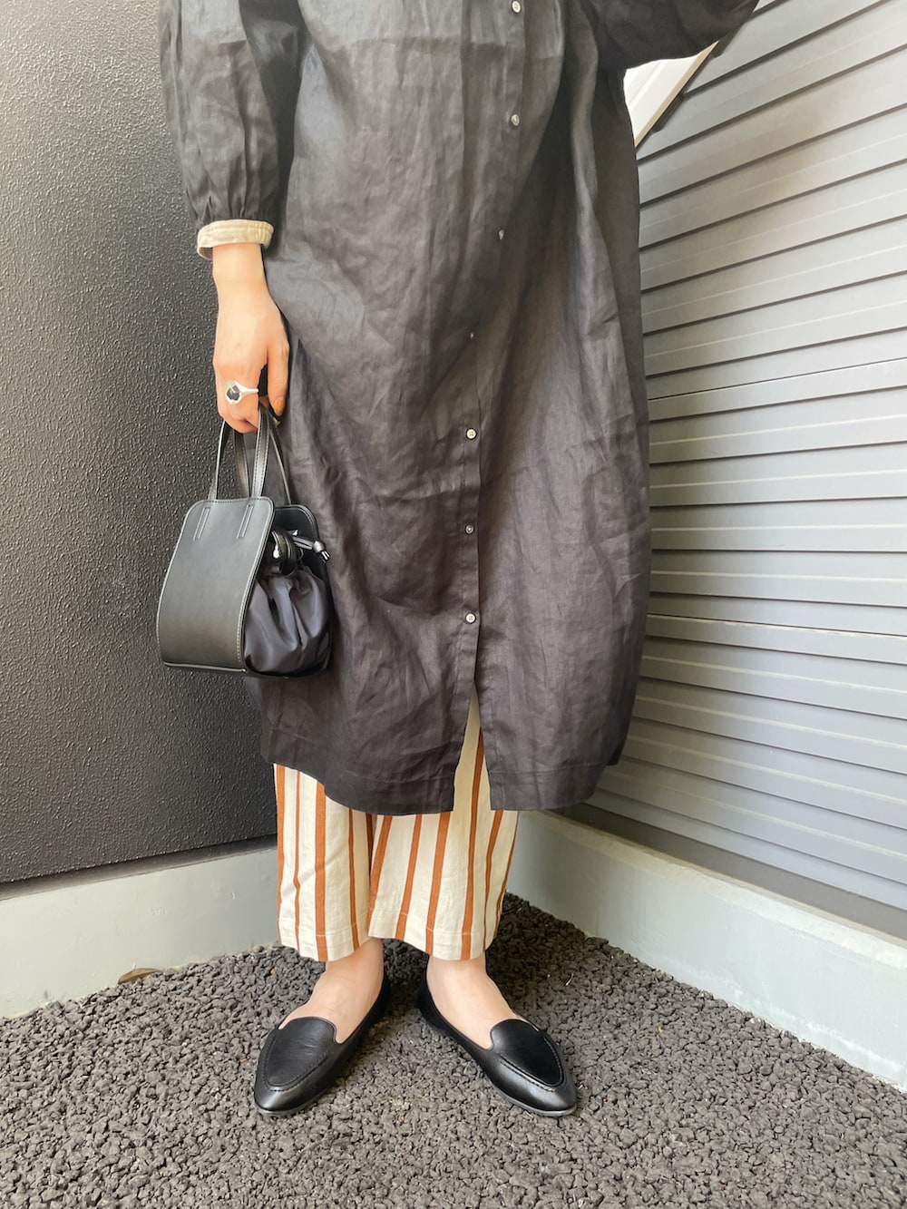 ブラック系のショルダーバッグ、ブラック系のスリッポン、ホワイト系のパンツを着用したレディースの春コーディネートの3枚目の写真