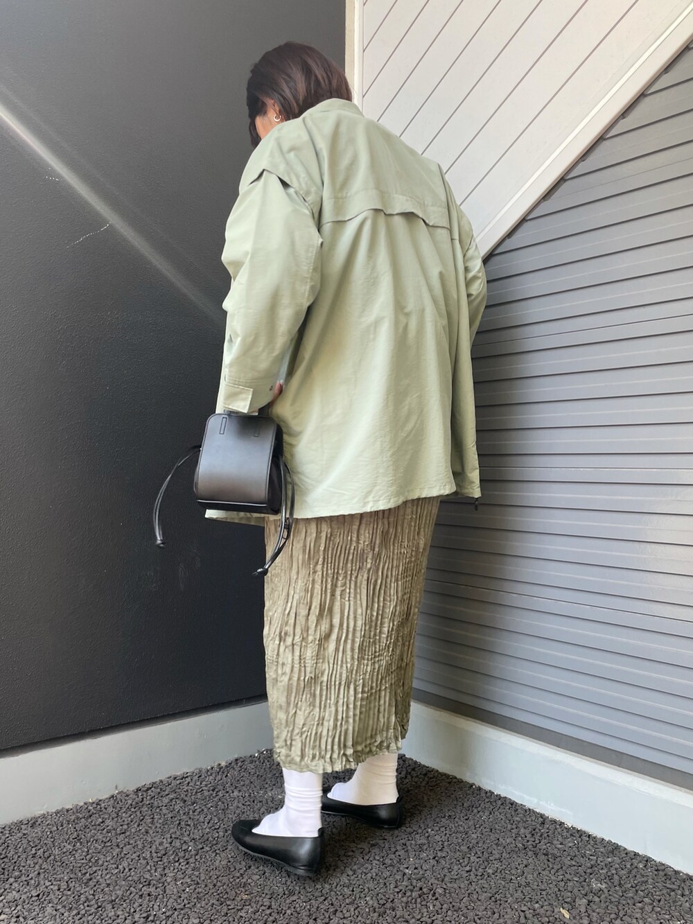 グリーン系のポンチョ、ブルー系のワンピース、ブラック系のスリッポンを着用したレディースの春コーディネートの2枚目の写真