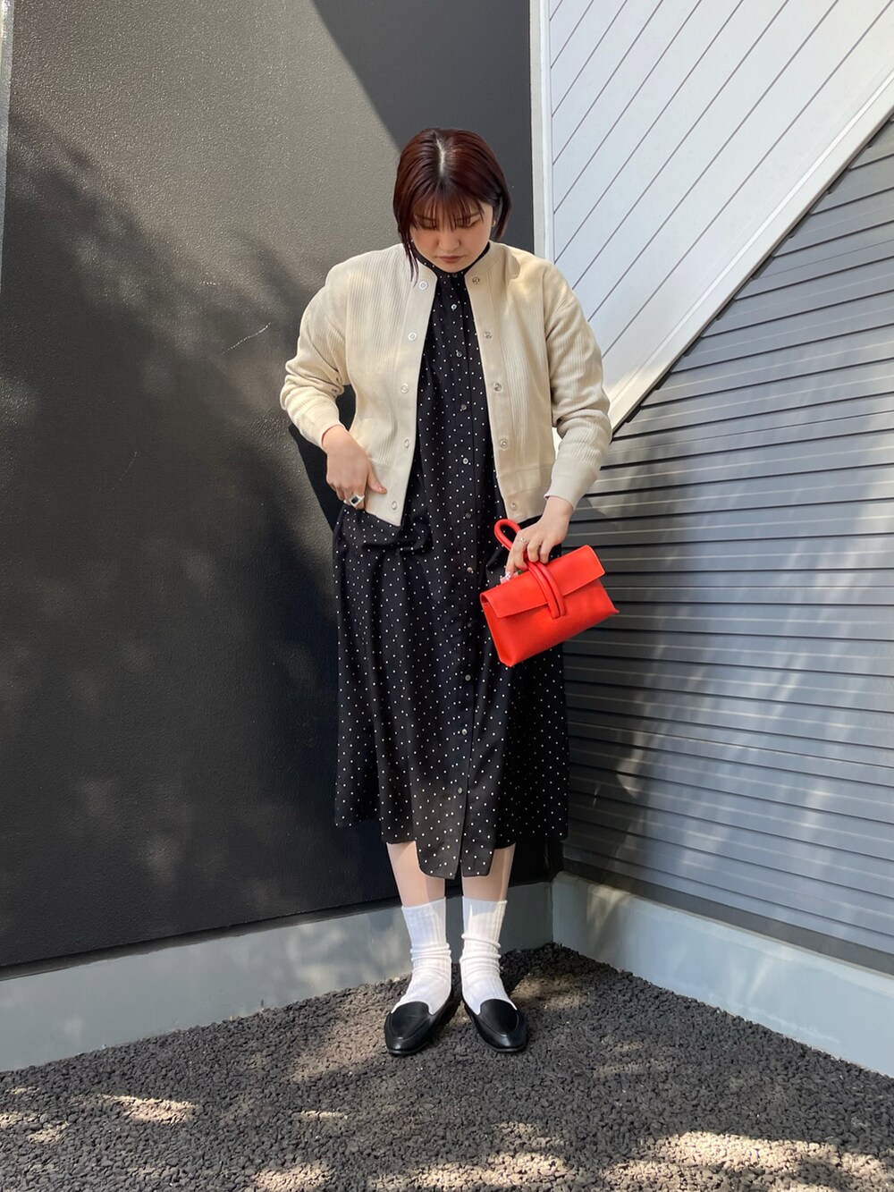 ブラック系のワンピース、ベージュ系のカーディガン/ボレロ、レッド系のショルダーバッグを着用したレディースの冬コーディネートの2枚目の写真