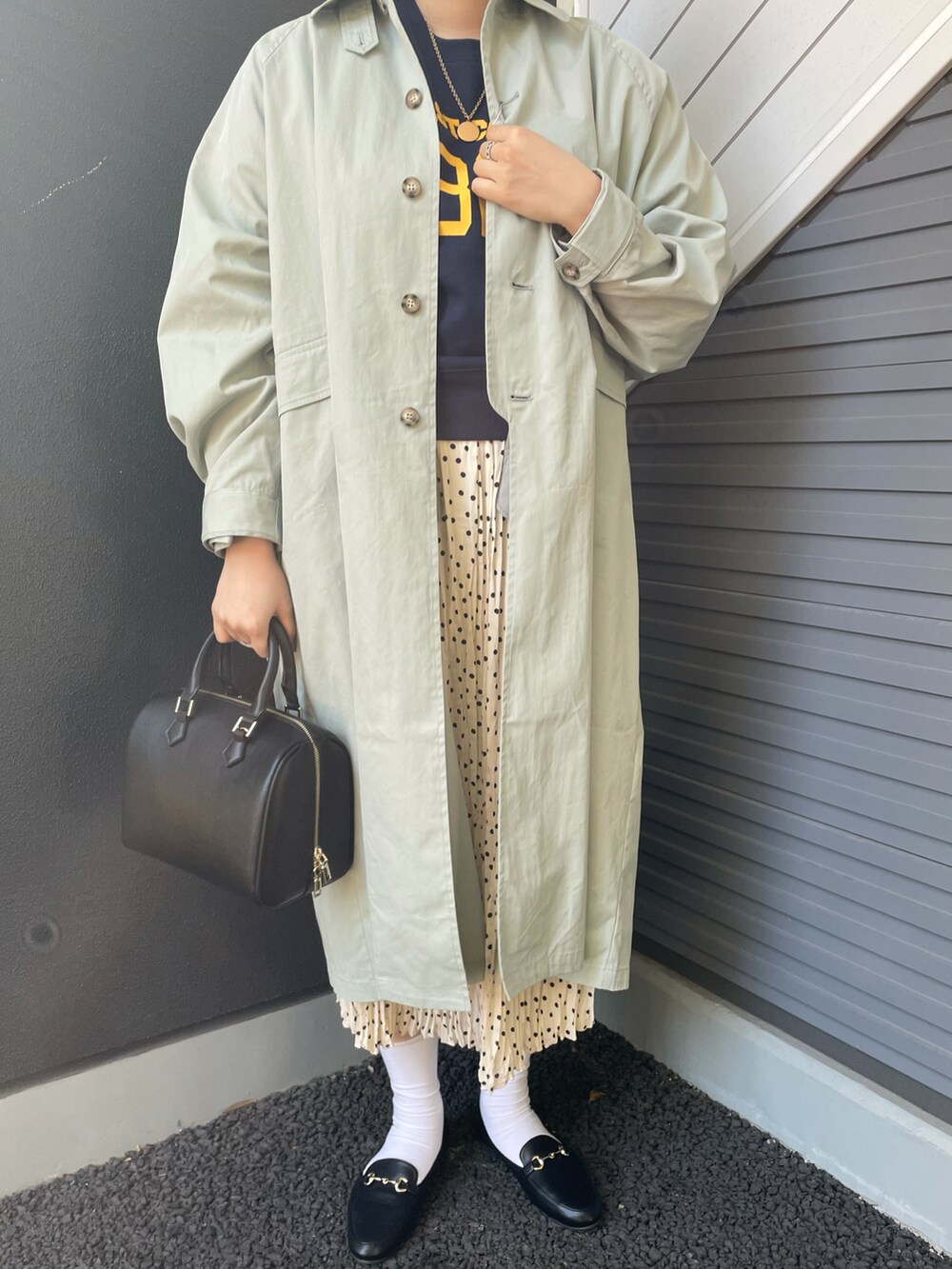 グリーン系のステンカラーコート、ブルー系のスウェット、ホワイト系のスカートを着用したレディースの冬コーディネートの3枚目の写真