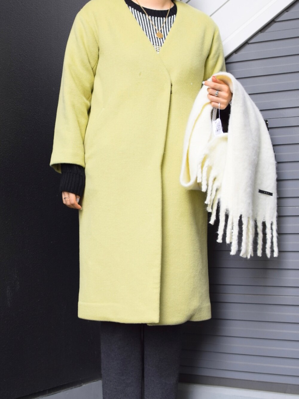 イエロー系のその他アウター、ブラック系のニット/セーター、グレー系のその他パンツを着用したレディースの冬コーディネートの2枚目の写真