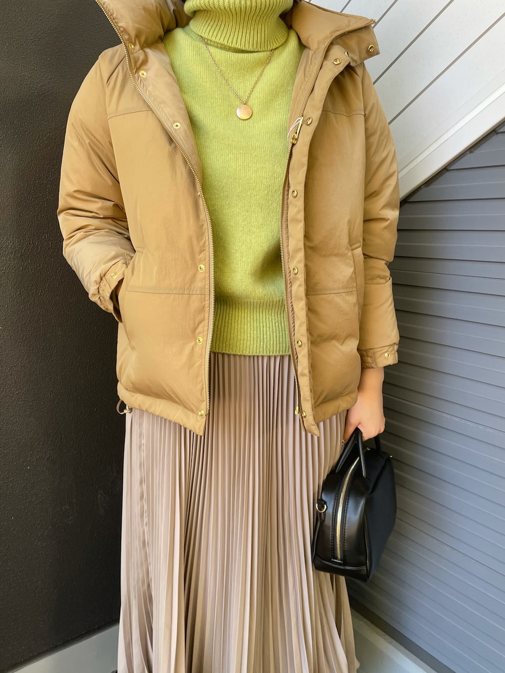 グリーン系のニット/セーター、ベージュ系のダウンジャケット/コート、ブラック系のボストンバッグを着用したレディースの冬コーディネートの3枚目の写真