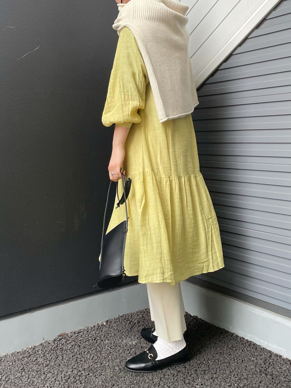 ブラック系のローファー、ブラック系のショルダーバッグ、イエロー系のワンピースを着用したレディースの冬コーディネートの3枚目の写真