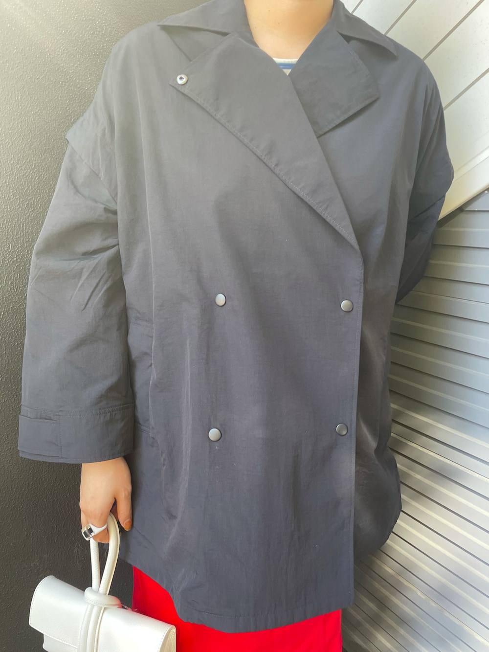 ブルー系のポンチョ、ホワイト系のショルダーバッグ、レッド系のスカートを着用したレディースの冬コーディネートの3枚目の写真